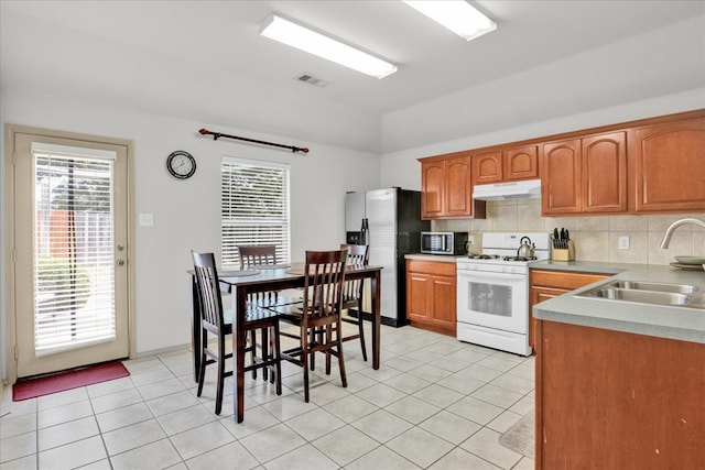 kitchen featuring light tile patterned flooring, stainless steel appliances, sink, a healthy amount of sunlight, and decorative backsplash