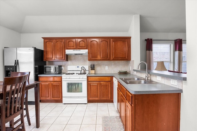 kitchen featuring backsplash, white appliances, sink, light tile patterned floors, and lofted ceiling