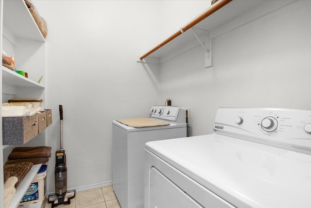 laundry area with washer and clothes dryer and light tile patterned floors