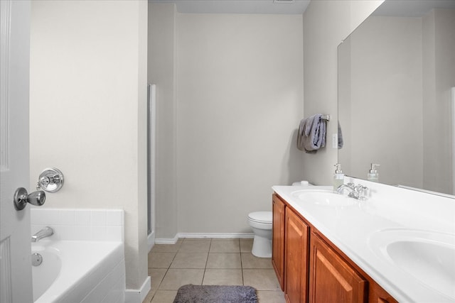 bathroom featuring tile patterned flooring, vanity, tiled bath, and toilet