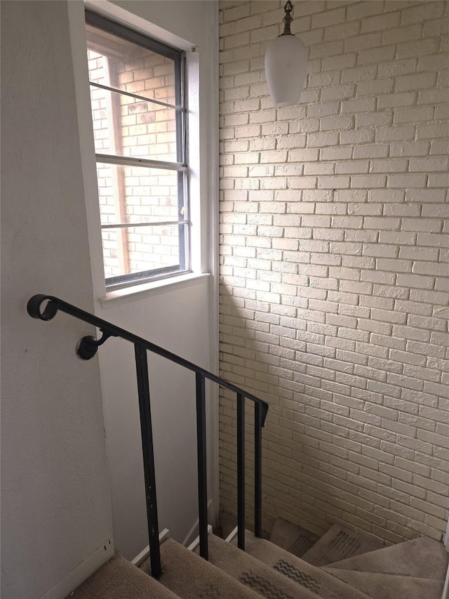 staircase featuring brick wall