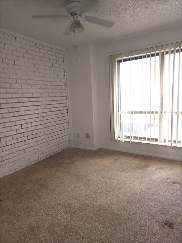 spare room with ceiling fan, brick wall, a textured ceiling, and carpet flooring