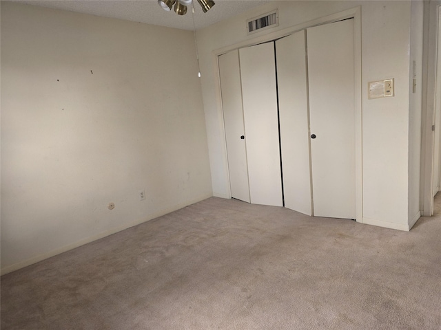 unfurnished bedroom with a textured ceiling and light colored carpet