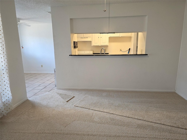 unfurnished living room with sink, light tile patterned flooring, a textured ceiling, and ceiling fan