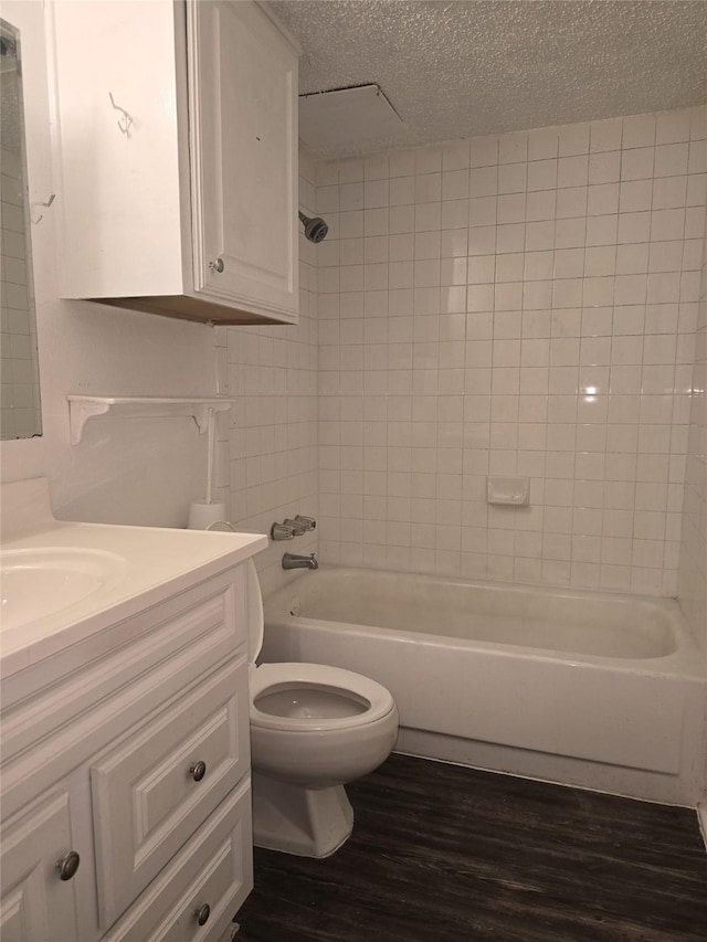 full bathroom featuring toilet, hardwood / wood-style floors, a textured ceiling, vanity, and tiled shower / bath