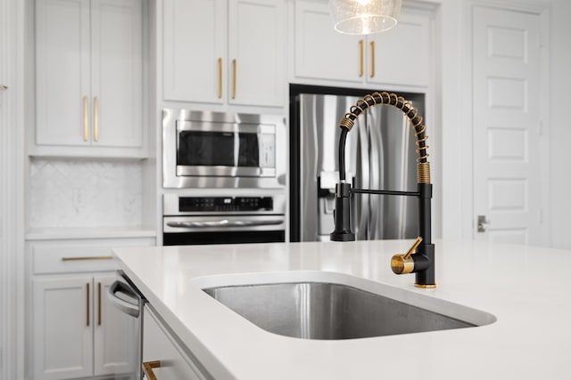 kitchen with decorative light fixtures, white cabinetry, and appliances with stainless steel finishes