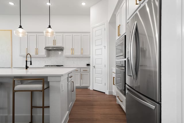 kitchen featuring dark hardwood / wood-style floors, pendant lighting, decorative backsplash, stainless steel appliances, and white cabinets