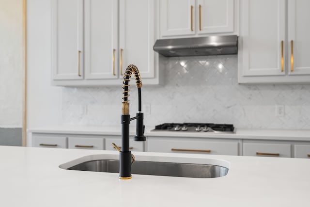 kitchen with backsplash, sink, and white cabinetry