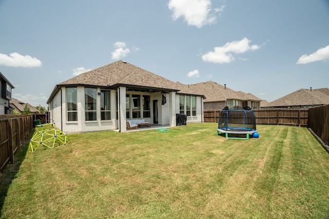 back of property featuring a lawn, a trampoline, and a patio