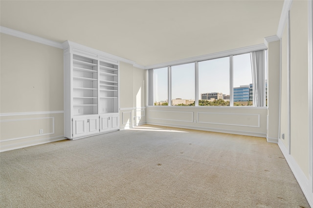 carpeted spare room with crown molding and built in shelves