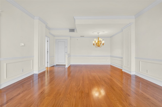 spare room featuring crown molding, an inviting chandelier, and hardwood / wood-style floors