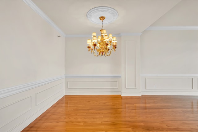 empty room featuring hardwood / wood-style floors, crown molding, and a notable chandelier