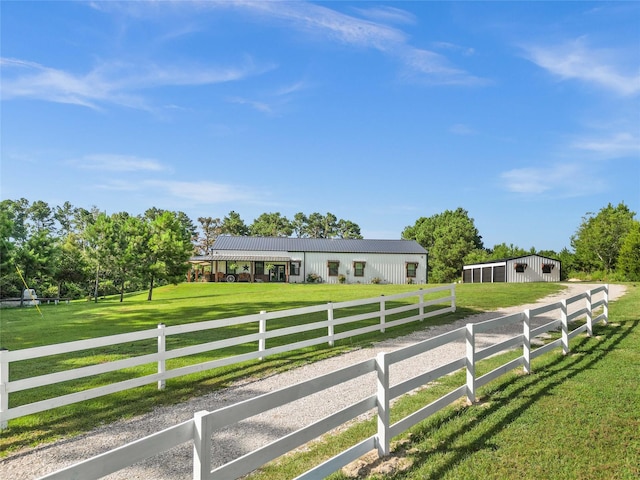 view of front of house featuring an outdoor structure, a rural view, and a front lawn