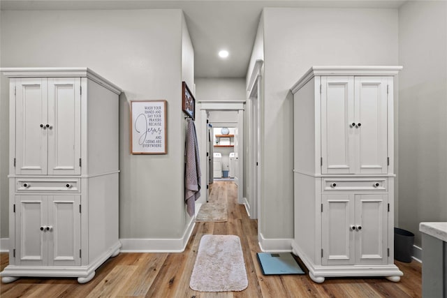 hallway with independent washer and dryer and light hardwood / wood-style floors