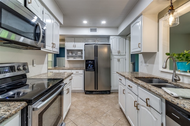 kitchen with sink, stainless steel appliances, light tile patterned floors, light stone counters, and white cabinets