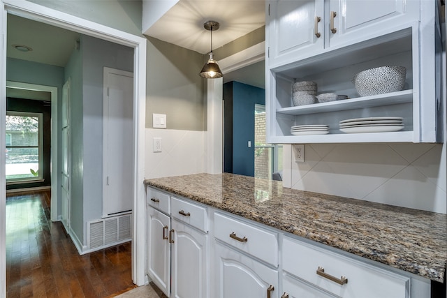 kitchen with pendant lighting, white cabinetry, backsplash, and dark stone counters