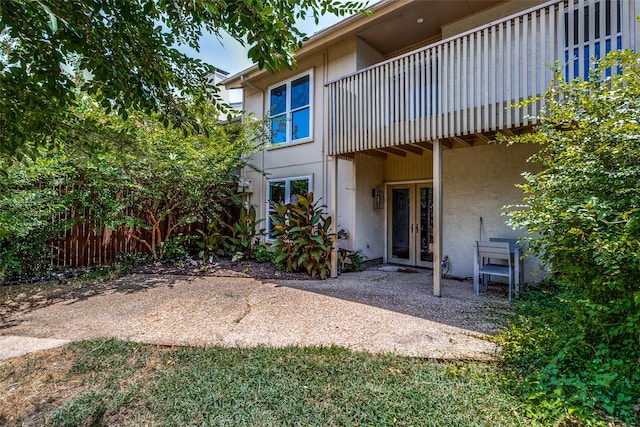 rear view of property featuring a balcony, a patio, and french doors