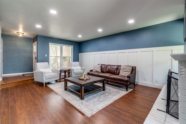 living room with a brick fireplace and dark wood-type flooring