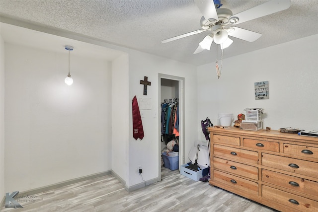 bedroom with a closet, a textured ceiling, ceiling fan, and light wood-type flooring