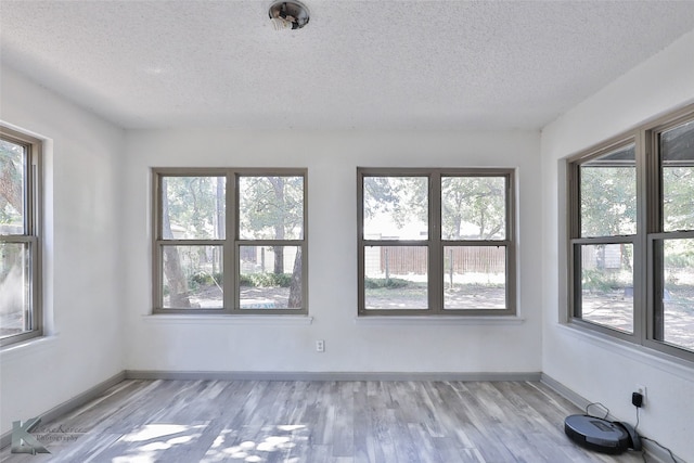 spare room with plenty of natural light, light wood-type flooring, and a textured ceiling