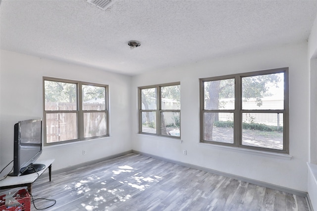 unfurnished living room featuring light wood-type flooring and a textured ceiling