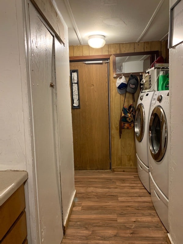 clothes washing area with washer and clothes dryer, a textured ceiling, and hardwood / wood-style floors