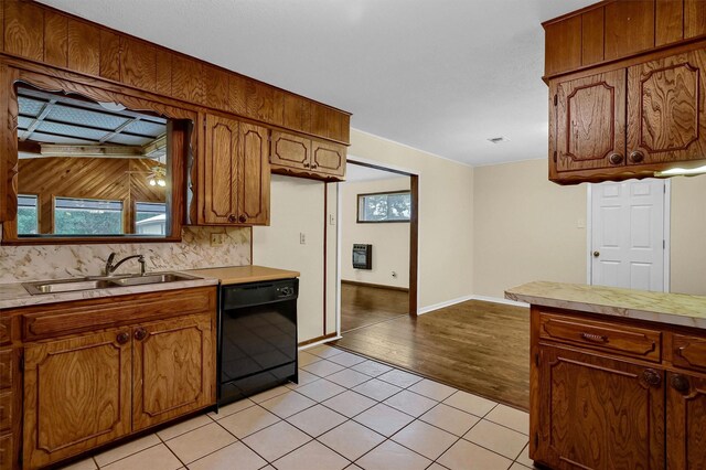 kitchen featuring black dishwasher, decorative backsplash, sink, and light wood-type flooring