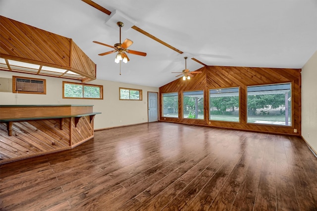 unfurnished living room featuring lofted ceiling, an AC wall unit, wood walls, ceiling fan, and hardwood / wood-style floors