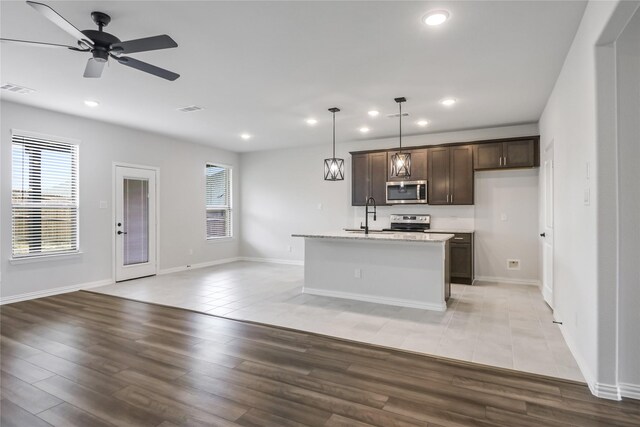 kitchen featuring ceiling fan, stainless steel appliances, light hardwood / wood-style floors, and an island with sink