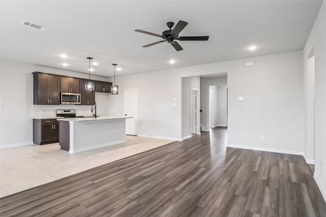 kitchen featuring a kitchen island with sink, stainless steel appliances, ceiling fan, and light hardwood / wood-style floors