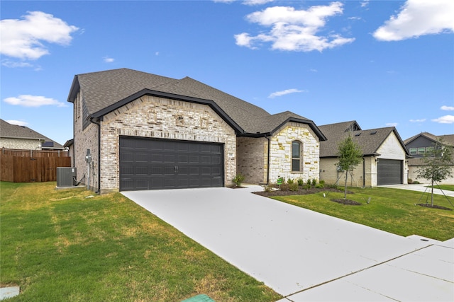 french country home featuring a garage, a front yard, and central AC unit