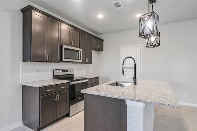 kitchen with a center island with sink, appliances with stainless steel finishes, tasteful backsplash, hanging light fixtures, and sink