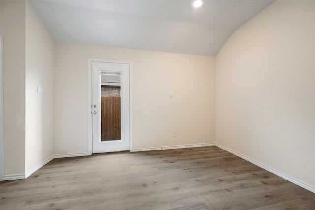 spare room with lofted ceiling and light wood-type flooring