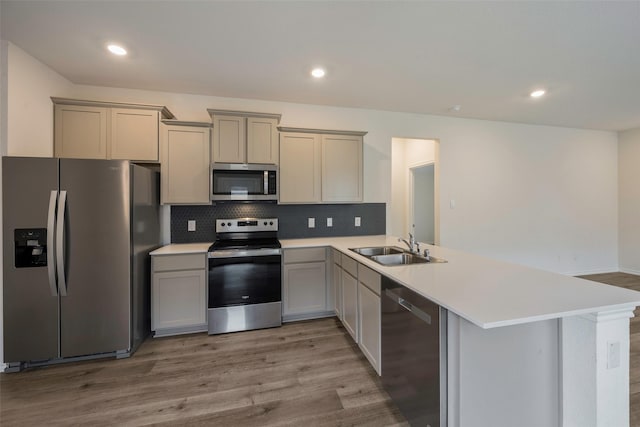 kitchen with sink, appliances with stainless steel finishes, backsplash, kitchen peninsula, and light wood-type flooring