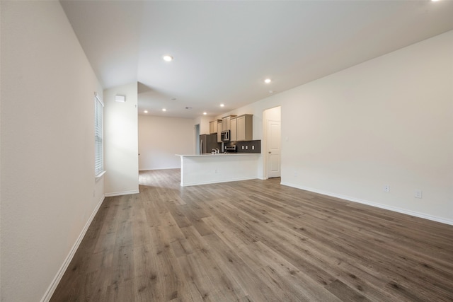 unfurnished living room featuring vaulted ceiling and light wood-type flooring