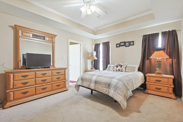 carpeted bedroom with ceiling fan, a raised ceiling, and crown molding