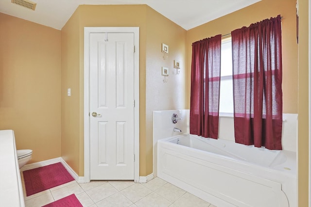 bathroom with a tub to relax in, tile patterned flooring, and toilet