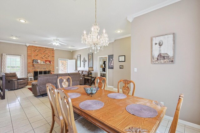 dining area with a fireplace, ceiling fan with notable chandelier, crown molding, brick wall, and light tile patterned floors