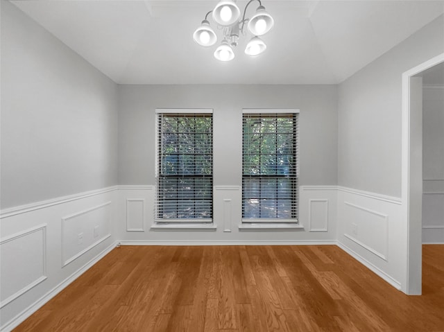 empty room featuring a notable chandelier and light wood-type flooring