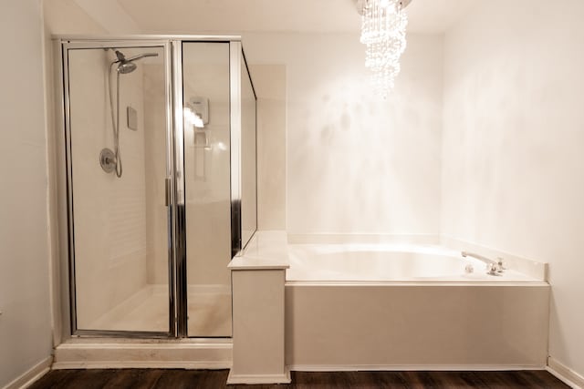 bathroom with shower with separate bathtub, hardwood / wood-style floors, and a chandelier