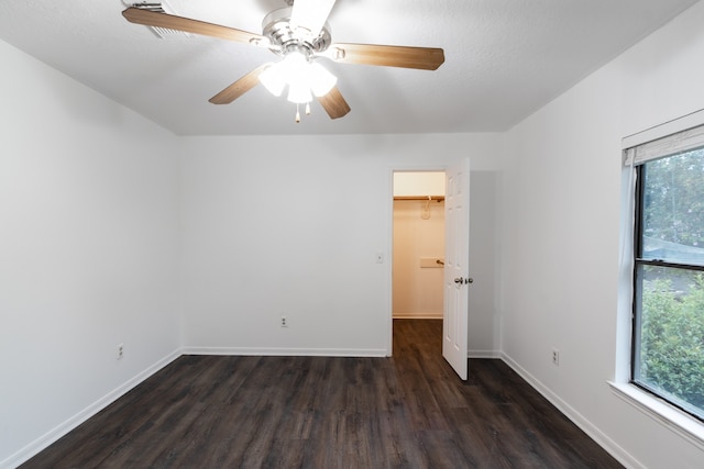 unfurnished bedroom with multiple windows, ceiling fan, hardwood / wood-style floors, and a walk in closet