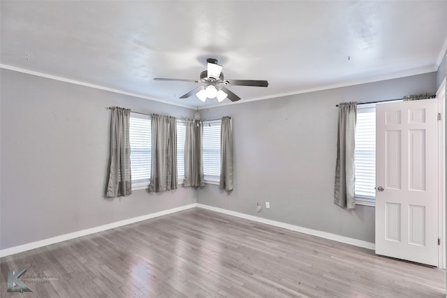 empty room with a wealth of natural light, ornamental molding, and light hardwood / wood-style floors