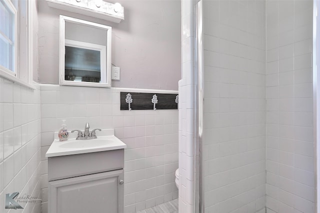 bathroom with toilet, vanity, and tile walls