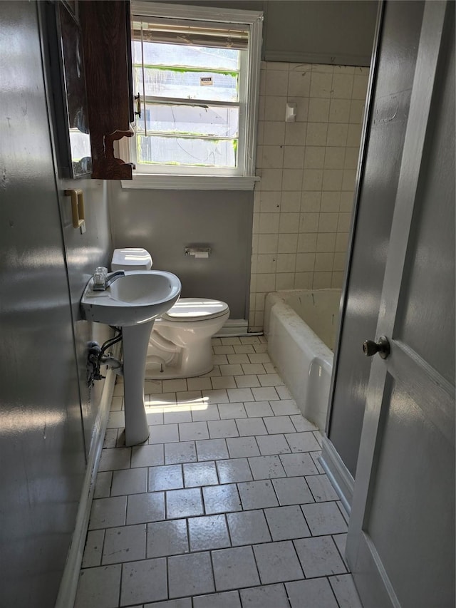 bathroom with tile patterned floors, a tub, and toilet