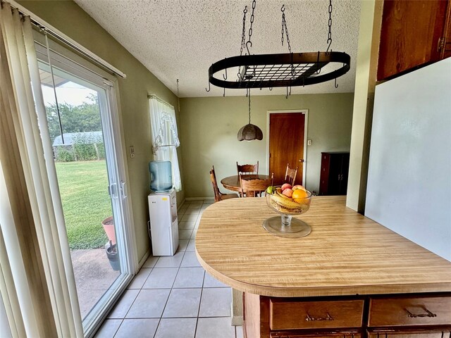 dining space with a textured ceiling and light tile patterned floors