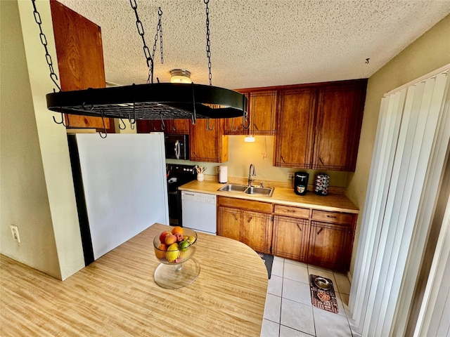 4506 Azalea Dr, Granbury, TX 76049 - kitchen with a sink, white appliances, a textured ceiling, light countertops, and brown cabinetry