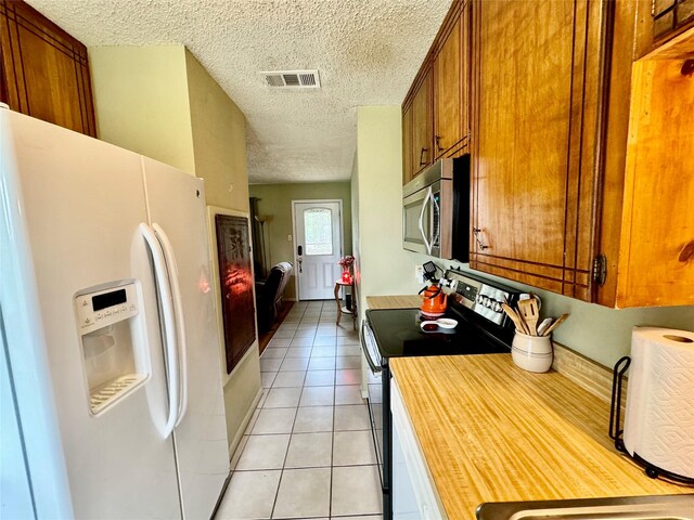 kitchen with a textured ceiling, light tile patterned floors, and appliances with stainless steel finishes