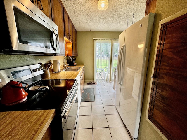 4506 Azalea Dr, Granbury, TX 76049 - kitchen with stainless steel appliances, a sink, butcher block countertops, a textured ceiling, and light tile patterned flooring