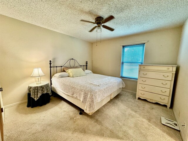 bedroom with ceiling fan, carpet flooring, and a textured ceiling