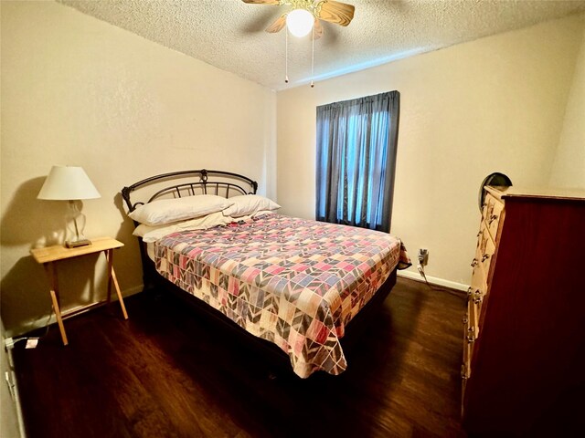 bedroom with ceiling fan, dark wood-type flooring, and a textured ceiling